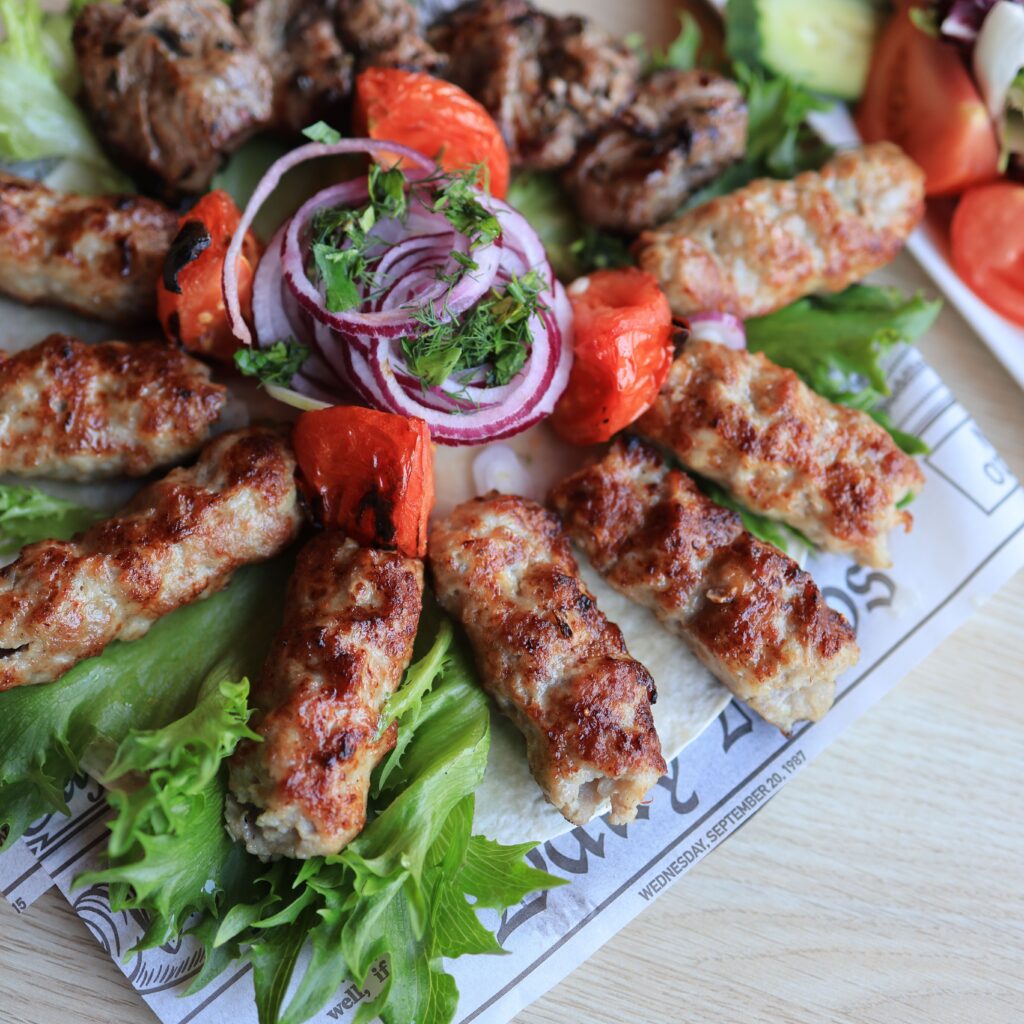 A tempting platter of grilled kebabs served with fresh vegetables and sauce.
